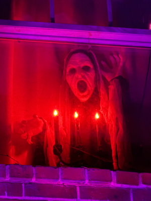 A spooky fiend in a window with a candelabra. 