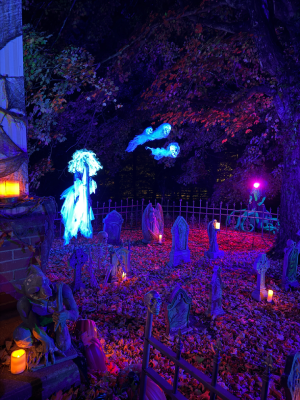 A Halloween graveyard with a fence, gravestones, a banshee, and graveyard spirits. 