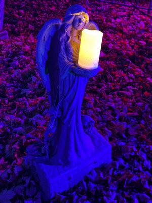 A gravestone of an angel being worshiped by skeletons. Engraved on the stone is regret