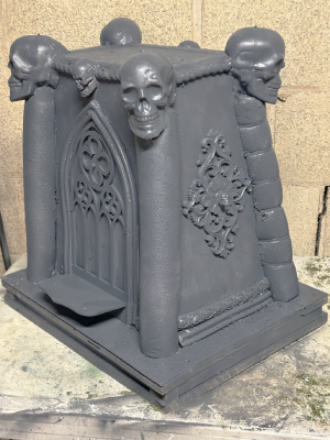 An unfinished Halloween prop. An altar with skulls and gothic detailing.