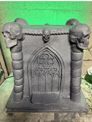 A fake Halloween altar painted to look like stone with skulls and gothic detailing.