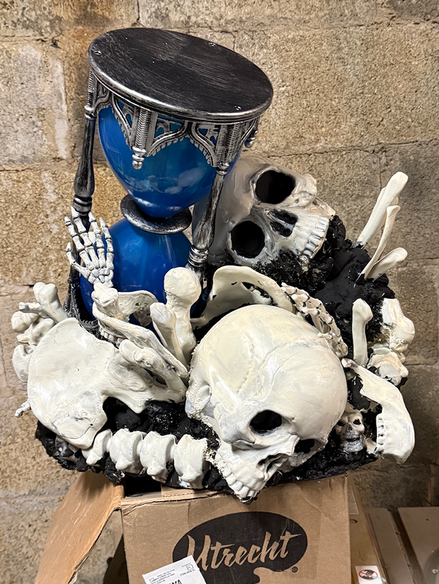 A pile of bones and skulls with an hourglass sticking out of it.