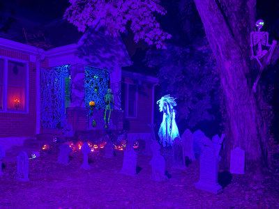 A blacklight Haloween scene. Th back drop is spiderwebs, there is a glowing Jackolantern on a stand, glowing bats hung from the ceiling, a spider on the webs, a green crawling skeleton and a green glowing skeleton waving hello. On the edge of the steps are 3 jackolanterns and a gargoyle. A few candles are around. Beside the porch is a row of Jackolanterns lit in different colors. Then a spooky graveyard haunted by a screaming Banshee. There is a skeleton in a tree with glowing green eyes.